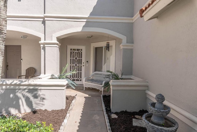 property entrance with covered porch and stucco siding