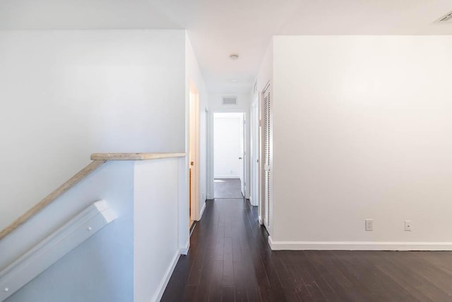 hall with dark wood-style floors, visible vents, and baseboards