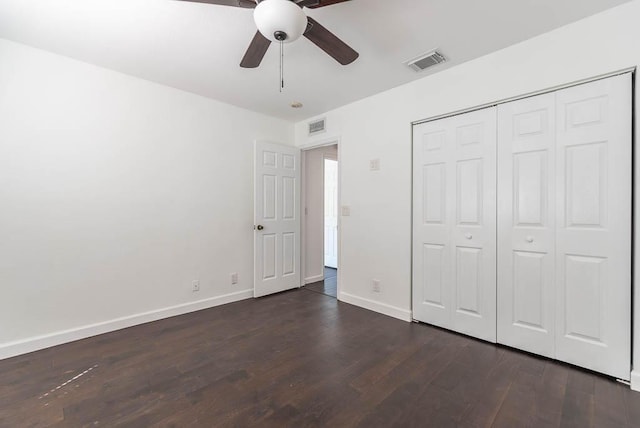 unfurnished bedroom with dark wood-style floors, visible vents, a closet, and baseboards