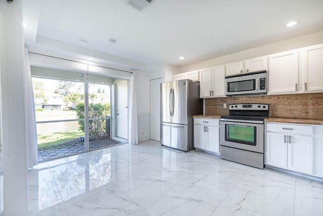 kitchen featuring visible vents, marble finish floor, backsplash, stainless steel appliances, and white cabinets