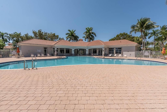 community pool with a patio and fence