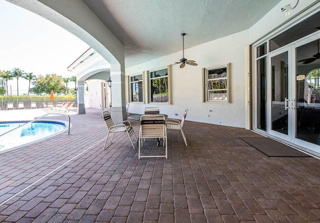 view of patio / terrace with fence, french doors, a community pool, outdoor dining area, and ceiling fan