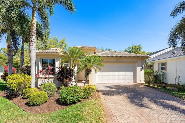 view of front of property featuring decorative driveway, a tile roof, an attached garage, and stucco siding