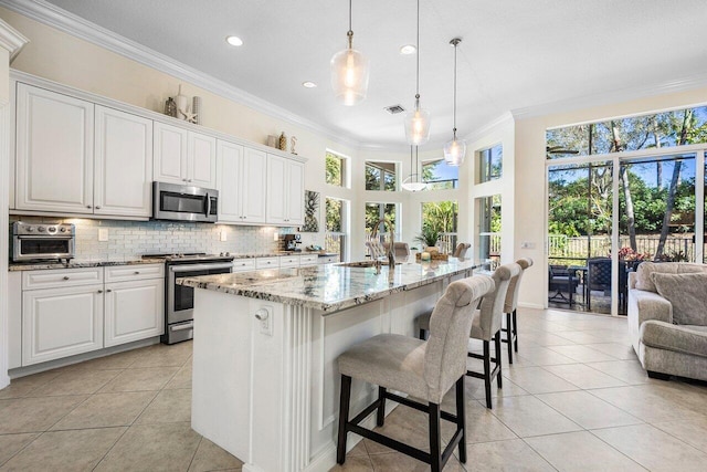 kitchen featuring light stone counters, stainless steel appliances, a sink, decorative backsplash, and crown molding