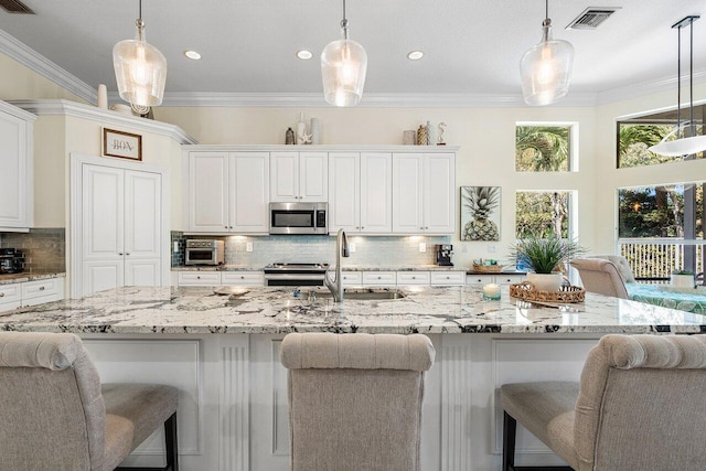 kitchen with stainless steel appliances, crown molding, a sink, and white cabinetry