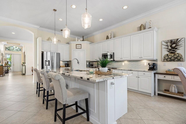 kitchen featuring light tile patterned floors, tasteful backsplash, arched walkways, and stainless steel appliances