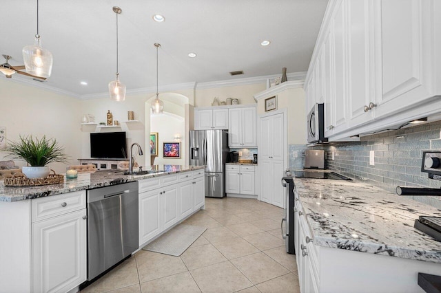 kitchen with arched walkways, crown molding, stainless steel appliances, white cabinets, and a sink