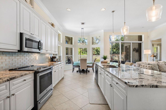 kitchen featuring a sink, white cabinets, appliances with stainless steel finishes, tasteful backsplash, and crown molding