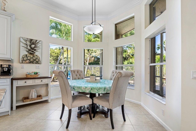 dining area with a towering ceiling, baseboards, ornamental molding, and light tile patterned flooring