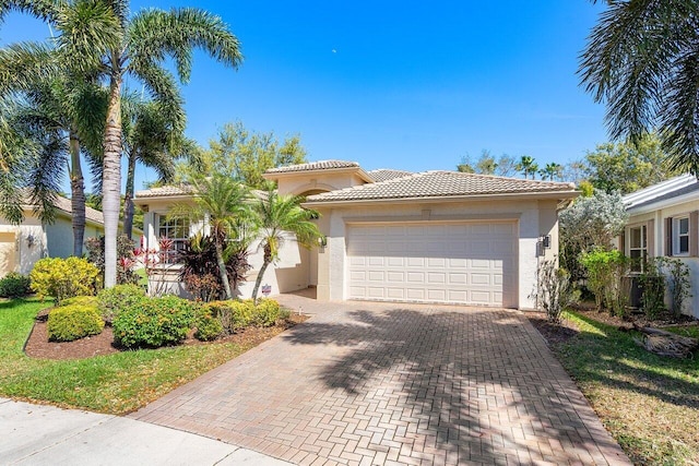 view of front of house featuring an attached garage, a tiled roof, decorative driveway, and stucco siding