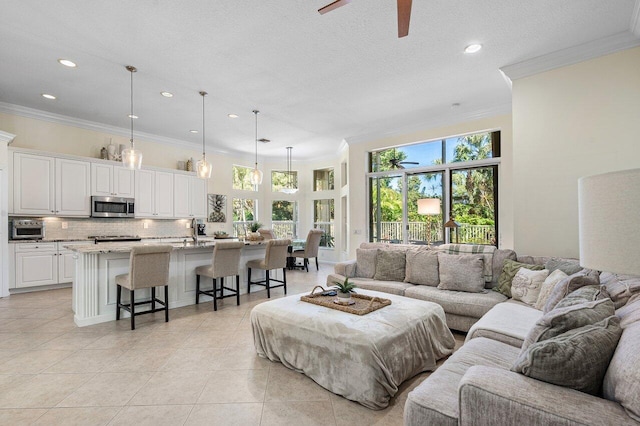 living room with light tile patterned floors, a textured ceiling, recessed lighting, a ceiling fan, and ornamental molding