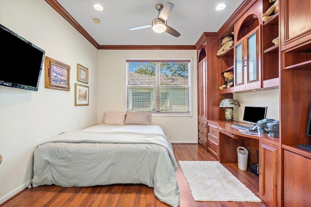 bedroom featuring baseboards, built in desk, wood finished floors, and crown molding