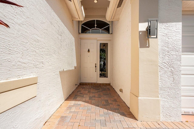 property entrance featuring a garage and stucco siding