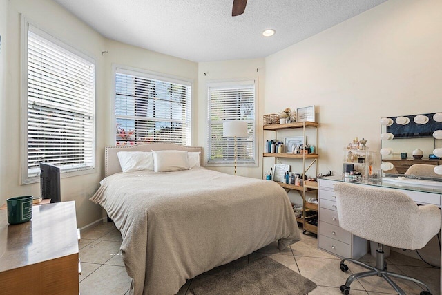 bedroom featuring a ceiling fan, baseboards, a textured ceiling, and light tile patterned flooring