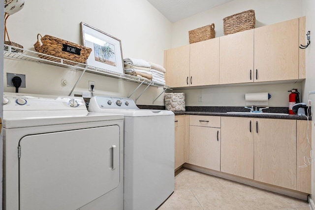 laundry area with a sink, light tile patterned floors, washing machine and dryer, and cabinet space