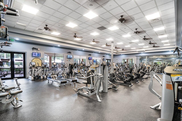 gym with ceiling fan, water heater, a drop ceiling, and visible vents