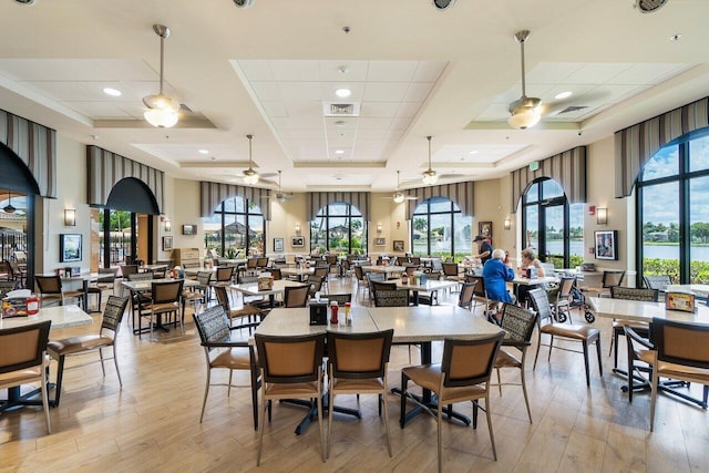 dining area featuring a ceiling fan, a high ceiling, visible vents, and light wood finished floors