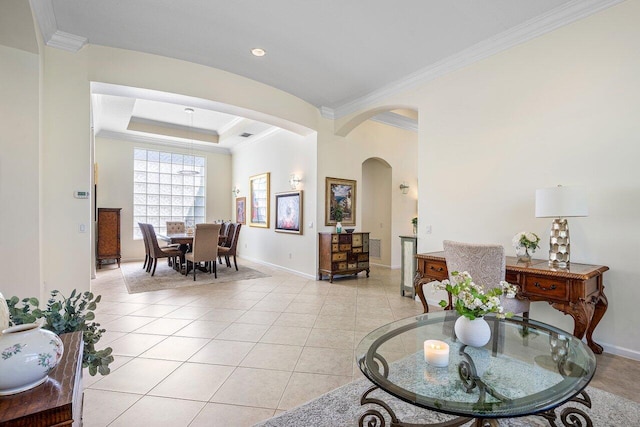 living room featuring arched walkways, a tray ceiling, ornamental molding, light tile patterned flooring, and baseboards