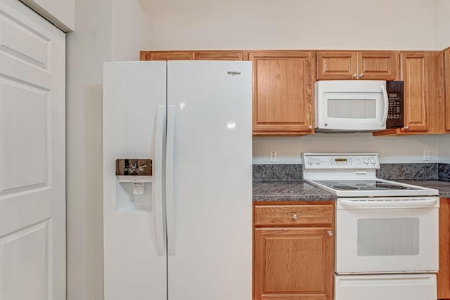 kitchen with dark countertops and white appliances