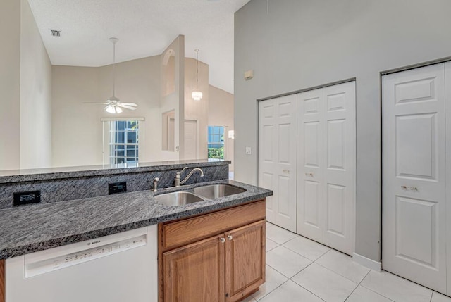 kitchen featuring light tile patterned floors, white dishwasher, a sink, visible vents, and dark stone countertops