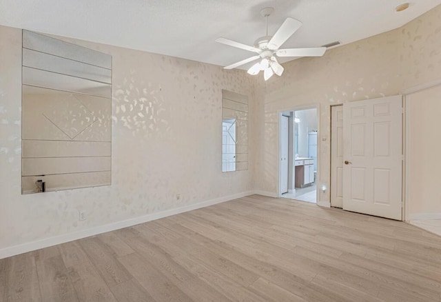 unfurnished bedroom featuring baseboards, wood finished floors, visible vents, and connected bathroom