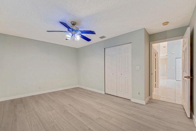 unfurnished bedroom with a closet, visible vents, baseboards, and light wood finished floors