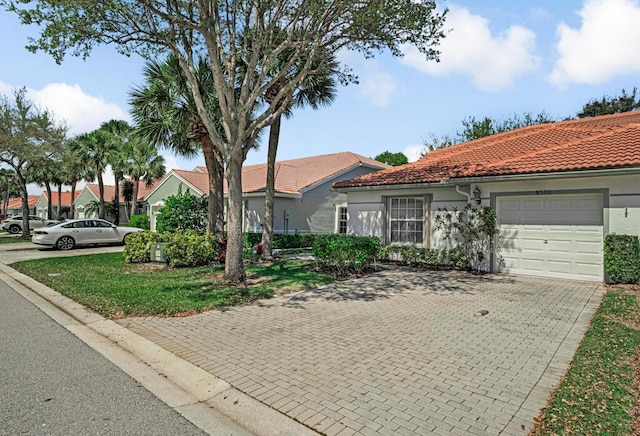 view of front of house featuring a garage, decorative driveway, a tiled roof, and stucco siding