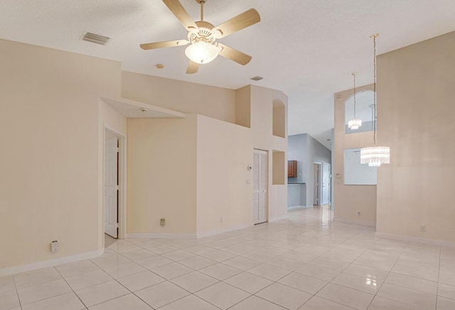 spare room featuring visible vents, light tile patterned flooring, baseboards, and ceiling fan with notable chandelier