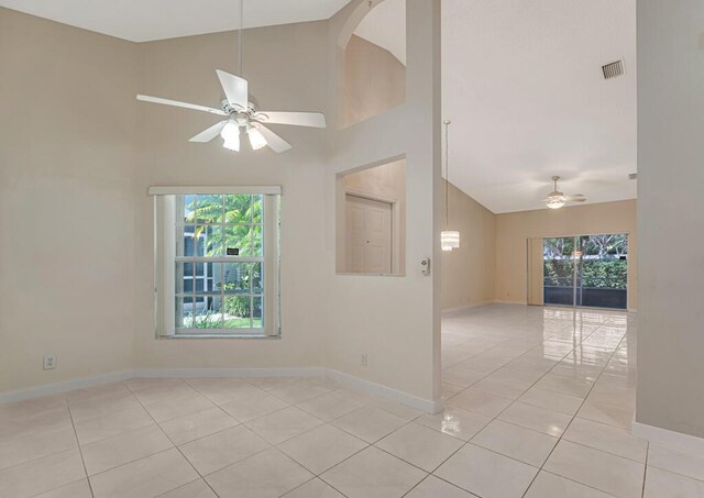 kitchen with high vaulted ceiling, light tile patterned flooring, a peninsula, white appliances, and dark stone counters