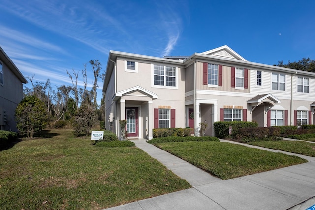 townhome / multi-family property with a front yard and stucco siding