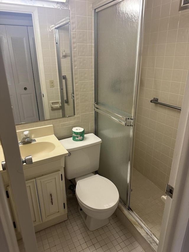 bathroom featuring tile walls, toilet, a stall shower, vanity, and tile patterned flooring