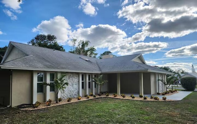 view of front of property featuring stucco siding, roof with shingles, and a front yard