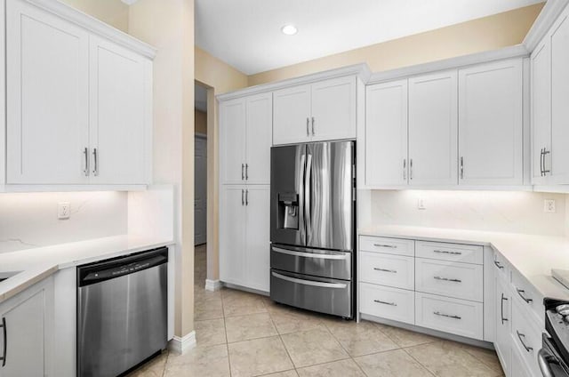 kitchen with white cabinetry, decorative backsplash, light tile patterned floors, and stainless steel appliances