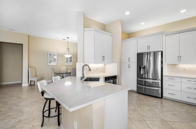 kitchen featuring a breakfast bar, a sink, stainless steel appliances, a peninsula, and white cabinets