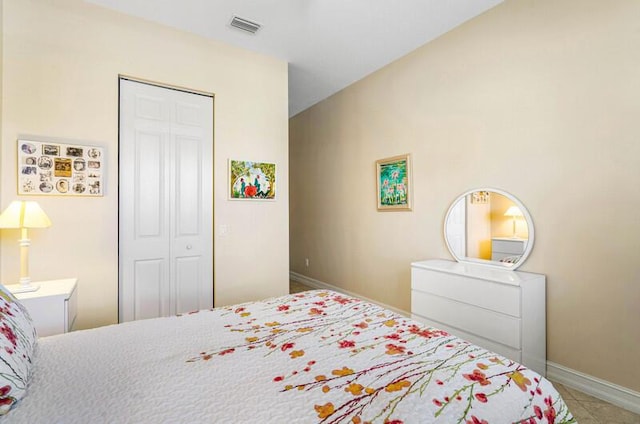 bedroom with a closet, visible vents, tile patterned flooring, and baseboards