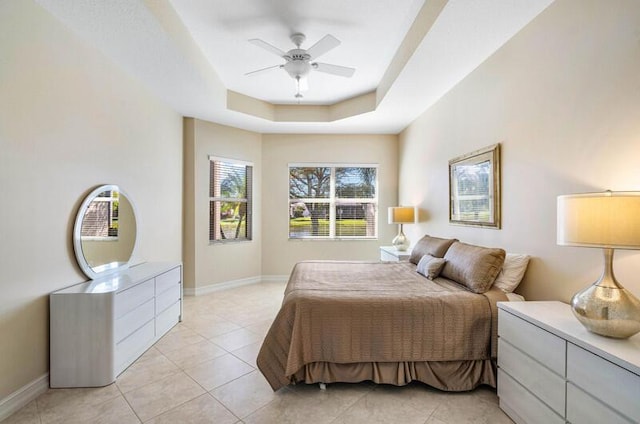 bedroom with a tray ceiling, baseboards, light tile patterned flooring, and a ceiling fan