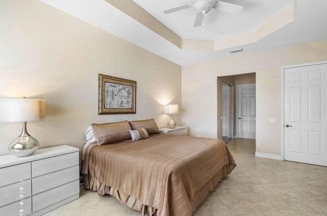 bedroom with a tray ceiling, baseboards, visible vents, and ceiling fan