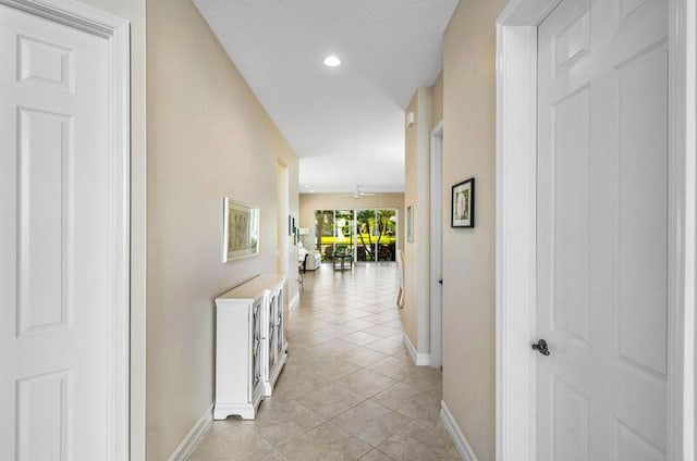 corridor featuring light tile patterned flooring, recessed lighting, and baseboards