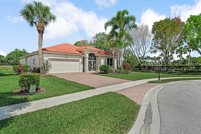 mediterranean / spanish-style home featuring an attached garage, stucco siding, a tile roof, decorative driveway, and a front yard