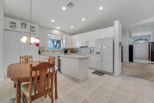 kitchen featuring a center island, white appliances, an inviting chandelier, light tile patterned flooring, and light countertops