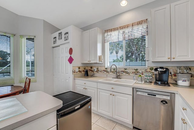 kitchen with a wealth of natural light, a sink, stainless steel dishwasher, and white cabinets