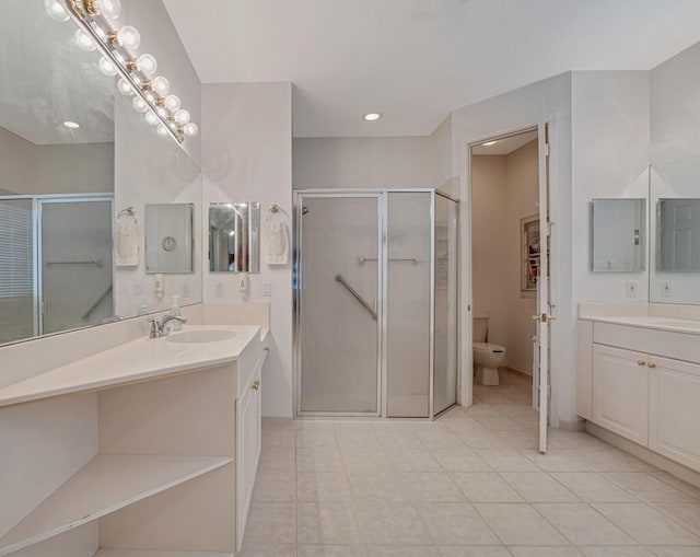 full bath with a sink, toilet, tile patterned floors, a stall shower, and two vanities