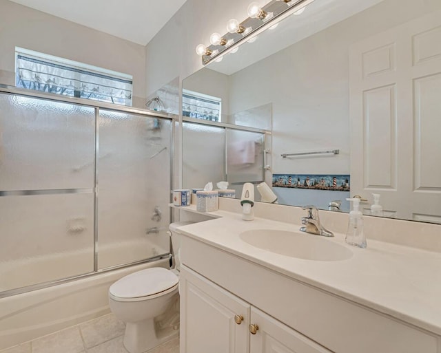bathroom with toilet, tile patterned floors, vanity, and combined bath / shower with glass door