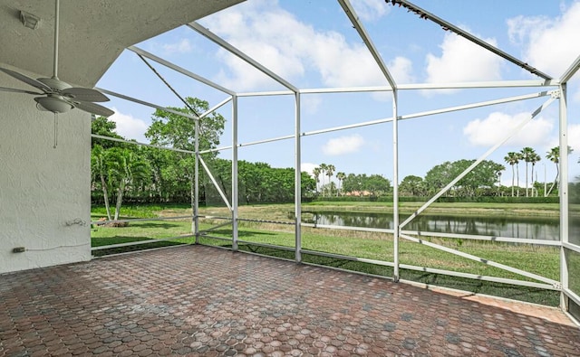 unfurnished sunroom featuring ceiling fan and a water view