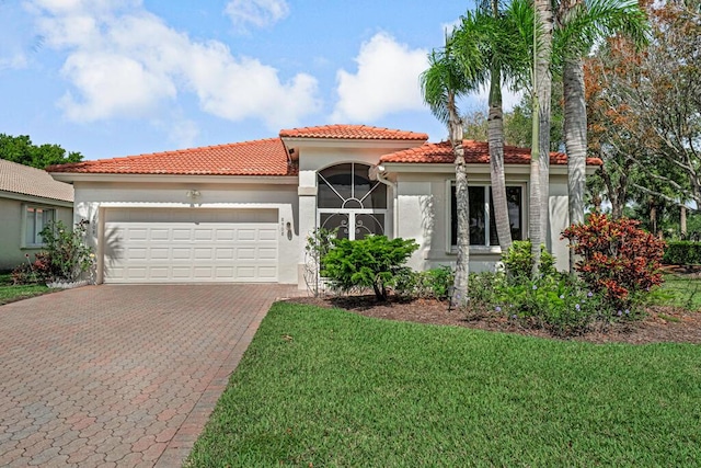 mediterranean / spanish home featuring an attached garage, stucco siding, a tile roof, a front lawn, and decorative driveway