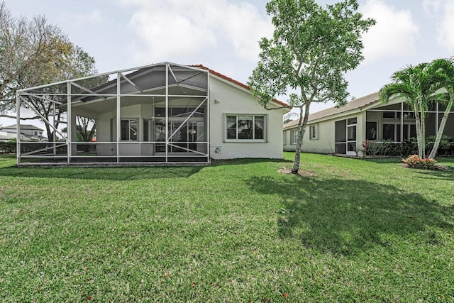 rear view of property featuring a yard, a lanai, and stucco siding