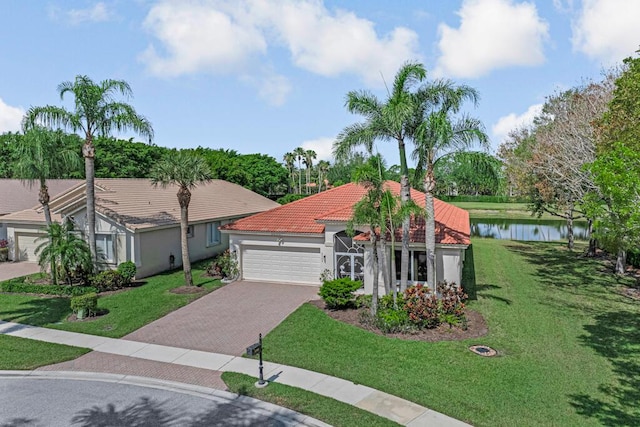 view of front of house featuring an attached garage, a tile roof, stucco siding, decorative driveway, and a water view