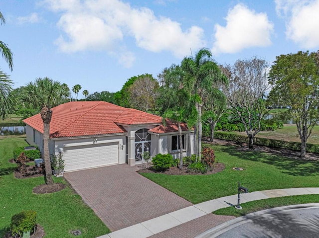 mediterranean / spanish house with an attached garage, stucco siding, a tile roof, a front lawn, and decorative driveway