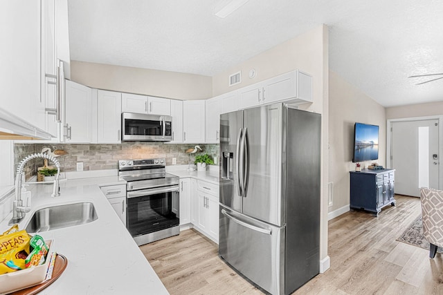 kitchen with light countertops, appliances with stainless steel finishes, a sink, and white cabinetry