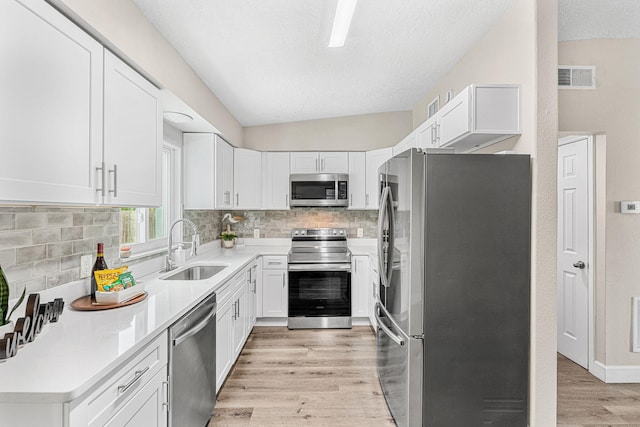 kitchen with light wood-style flooring, stainless steel appliances, a sink, visible vents, and white cabinets